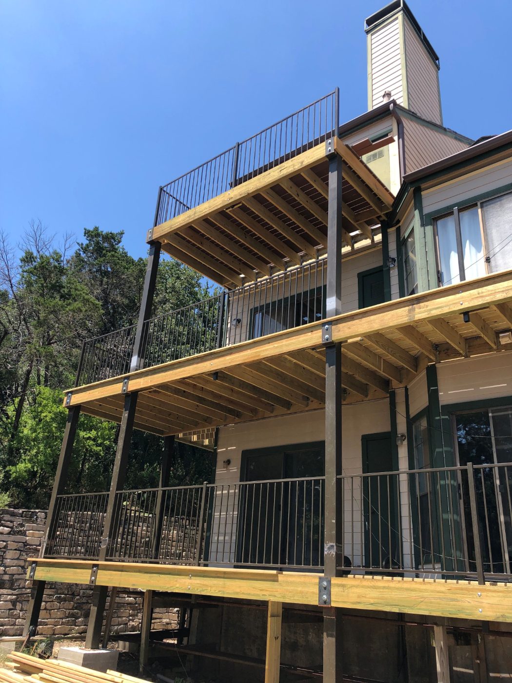 A Frame multi-level deck construction with steel posts on a hillside building