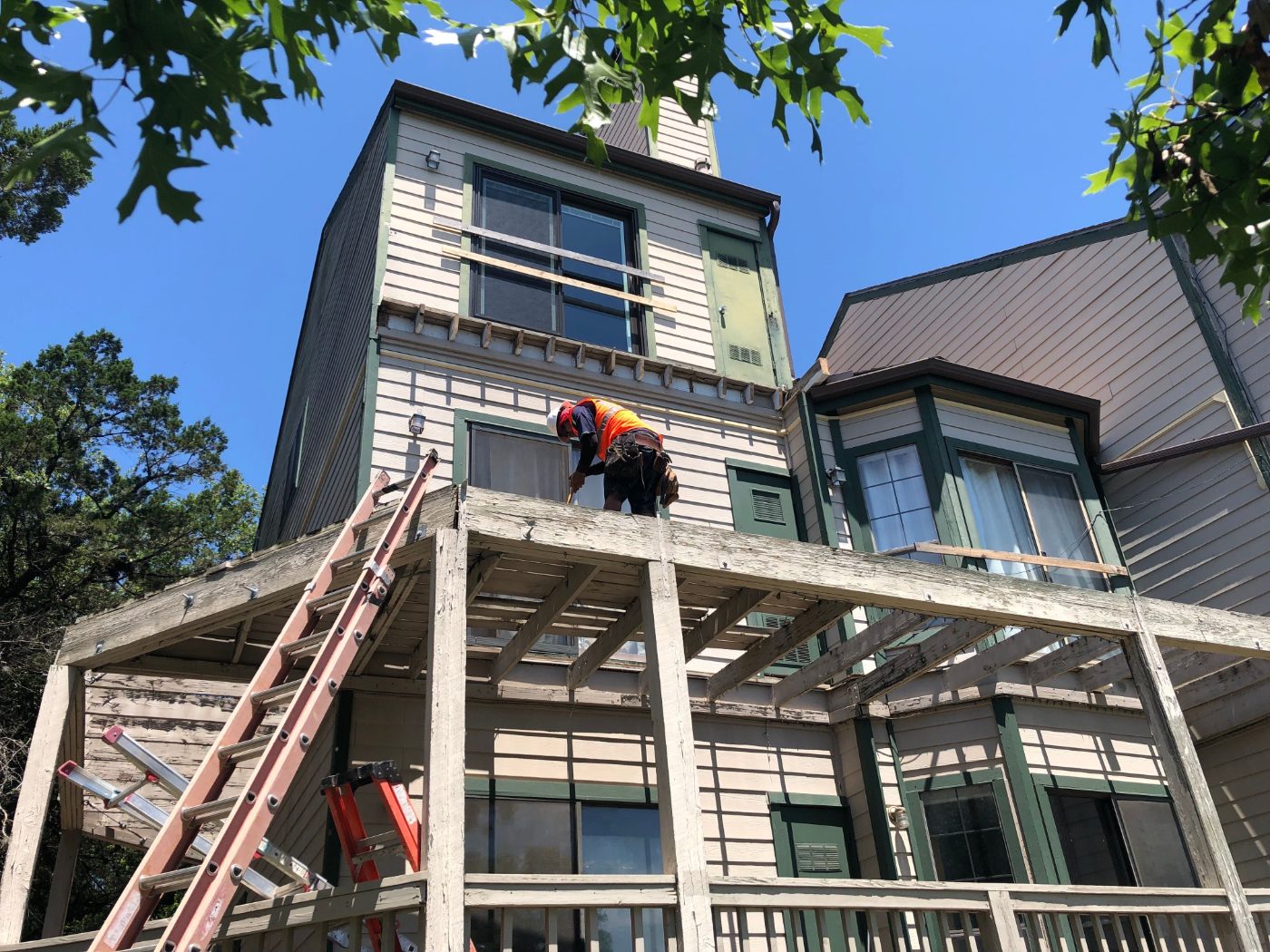 A Frame crew rebuilding an elevated deck and siding on a multi-story building