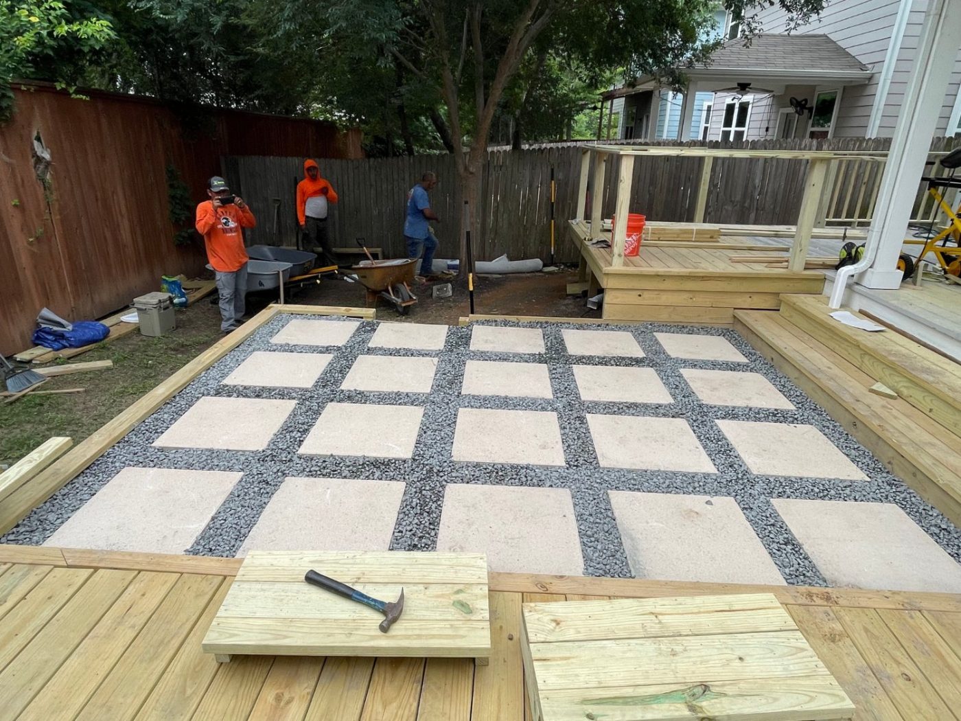 A Frame crew installing a paver-and-gravel patio between two new decks