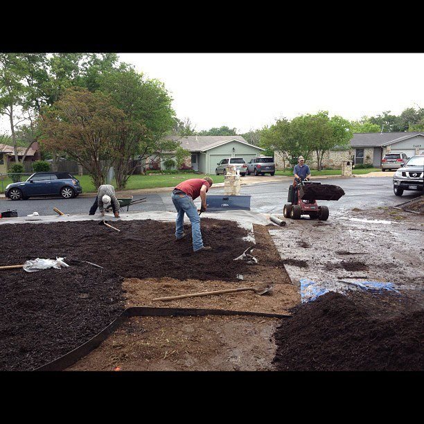A Frame crew spreading mulch and grading a front yard